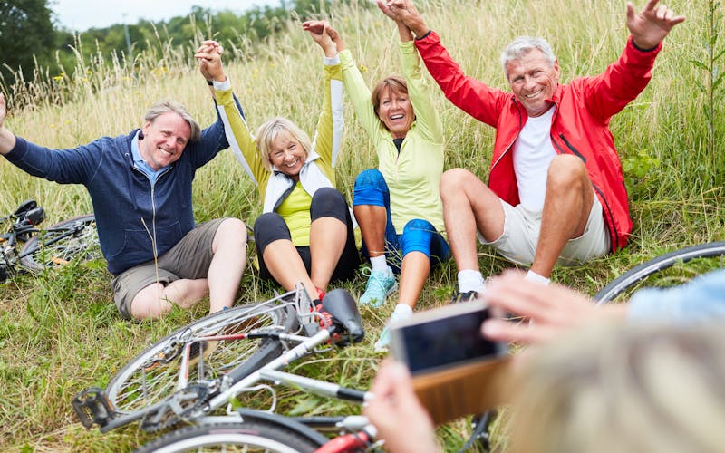 Menschen machen Pause von Fahrradtour im Gras und posen für ein gemeinsames Foto
