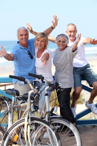 Lachende Menschengruppe mit Rädern an Strandpromenade