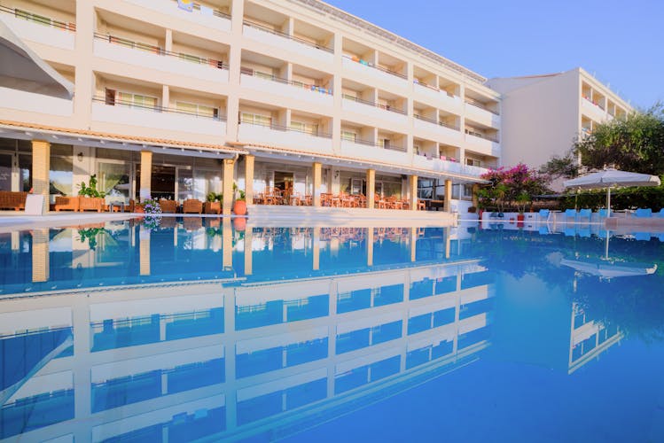 4 stöckiges weißes Hotelgebäude mit Balkonen und einem Pool 