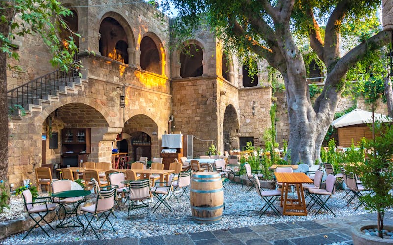 Griechisches Wirtshaus mit Tischen und Stühlen im großem Außenbereich