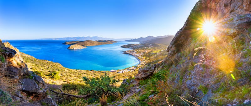 Blick zwischen Felsen auf traumhaft blaues Mittelmeer und kleiner Insel