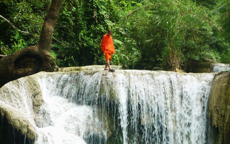 Mönch geht an Wasserfall-Kante entlang