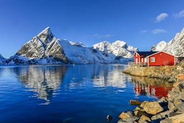 Schneebedeckte Berge mit rotem Holzhaus am Fjord