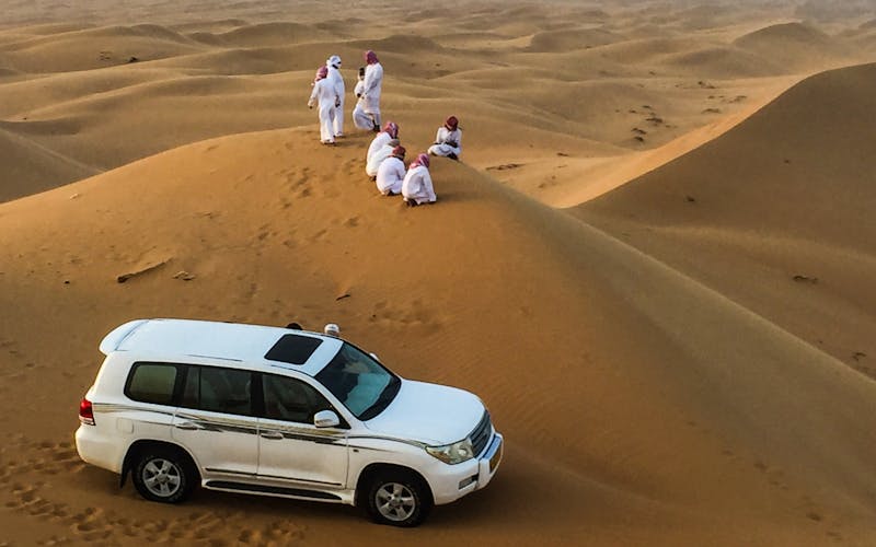 Menschen in weißen Tuniken auf Sanddüne in weiter Wüstenlandschaft
