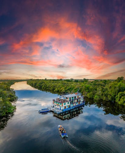 Kleines Schiff auf Amazonas bei Sonnenuntergang