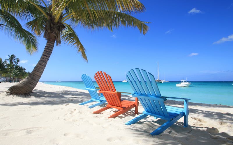 Farbige Holzstühle stehen am Strand