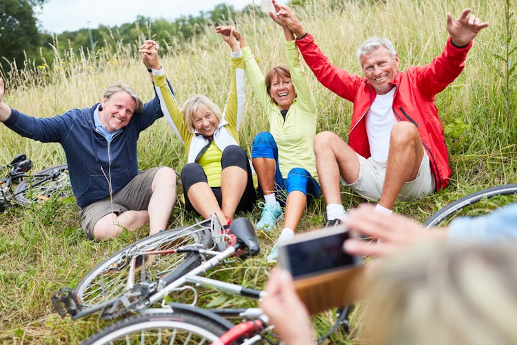Menschen machen Pause von Fahrradtour im Gras und posen für ein gemeinsames Foto